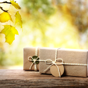 brown paper packages tied with string on a wooden surface and an autumn background