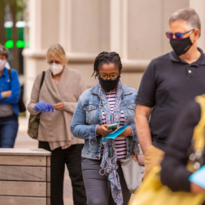 people standing in line outside with masks on