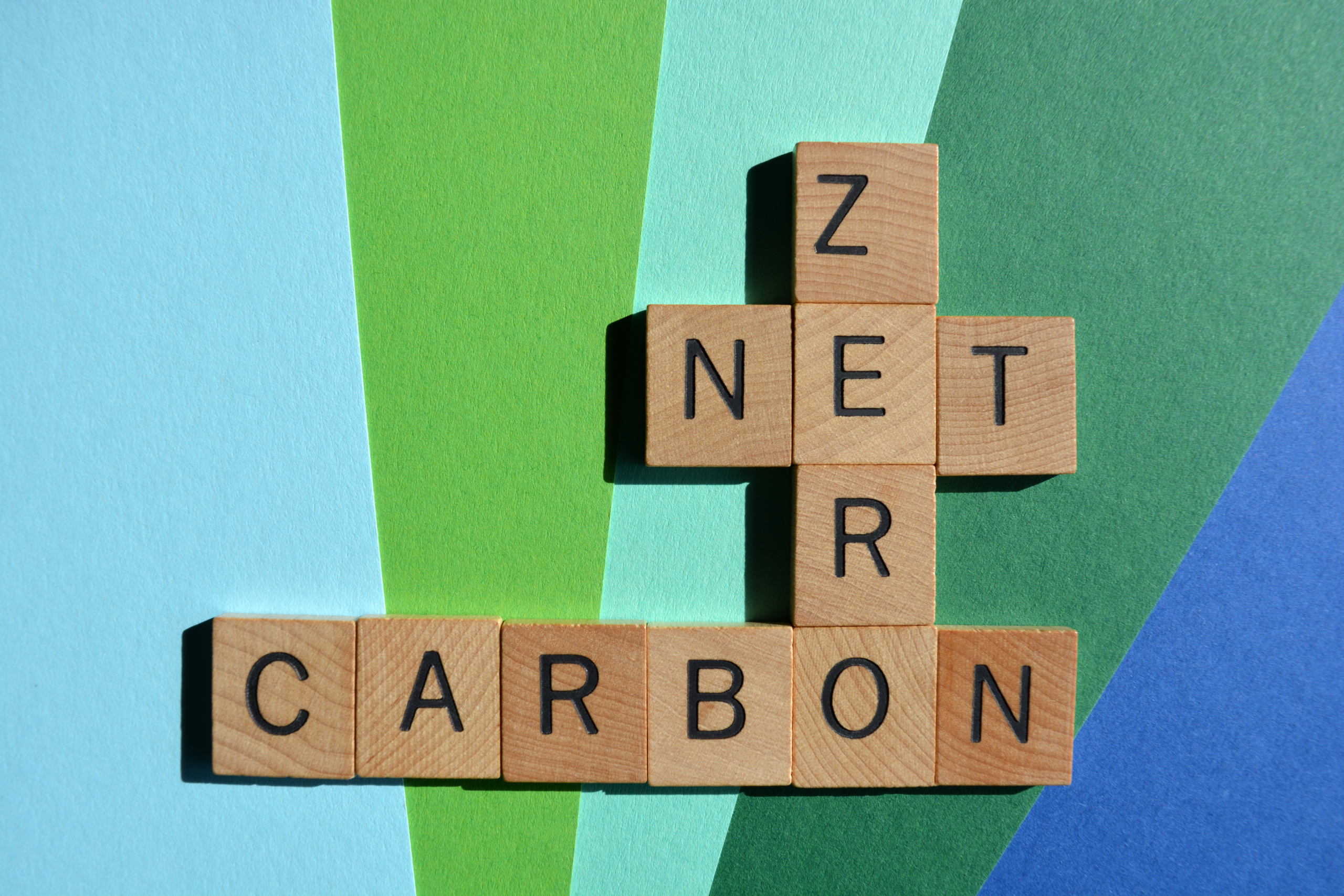 scrabble letters view from overhead spelling the words "net" "zero" and "carbon"